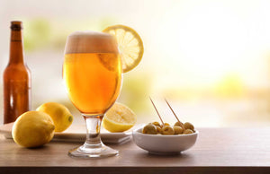 Craft beer with a lemon and a small bowl of olives.