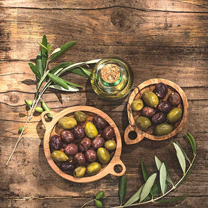 A vintage-looking table with olives, olive oil, and olive leaves